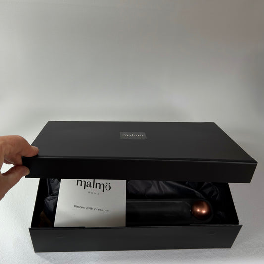 Black gift box with 'Malmö Home' branding on a light grey background
