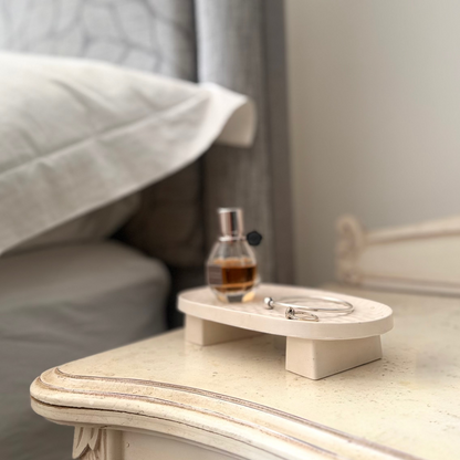 Malmo Home Poise Oval plinth on a bedside table styled with a perfume bottle and silver bangle
