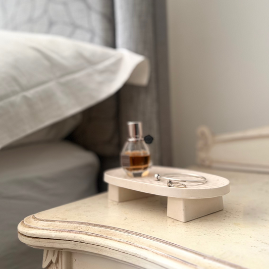 Malmo Home Poise Oval plinth on a bedside table styled with a perfume bottle and silver bangle
